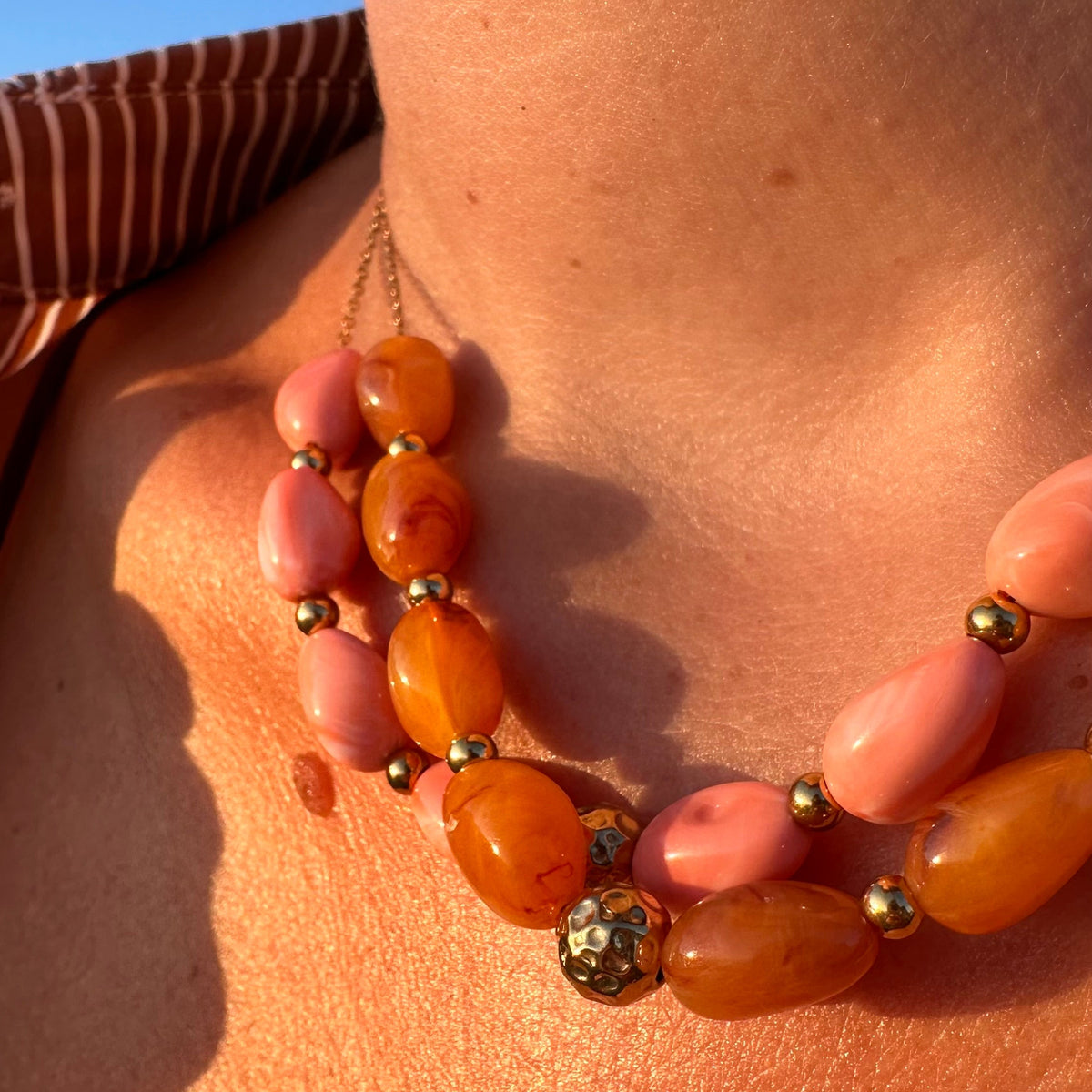Collier chaine doree avec grosses perles en resine orange et rose, porte au cou