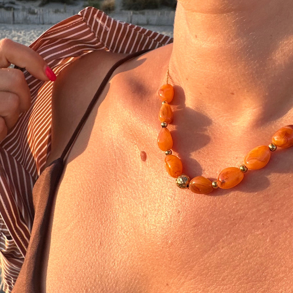 Collier de perles en resine orange porte au cou en exterieur