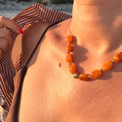 Collier de perles en resine orange porte au cou en exterieur